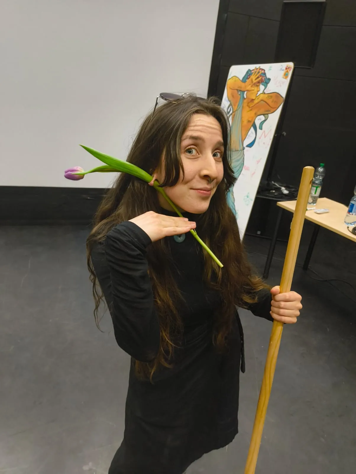 Team member posing with a tulip behind her ear and a broom handle