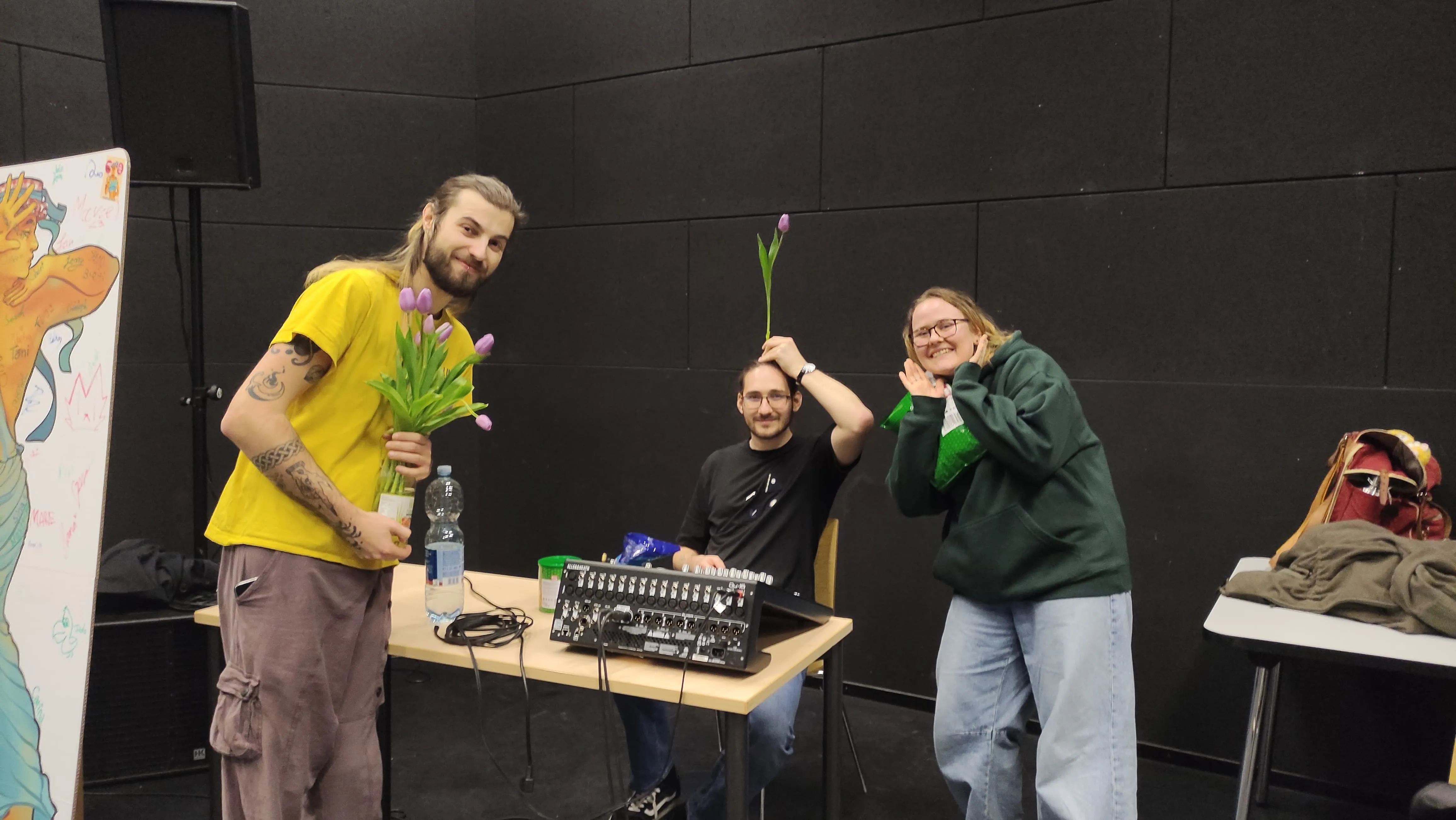 Three jam participants posing with purple tulips next to a mixing desk