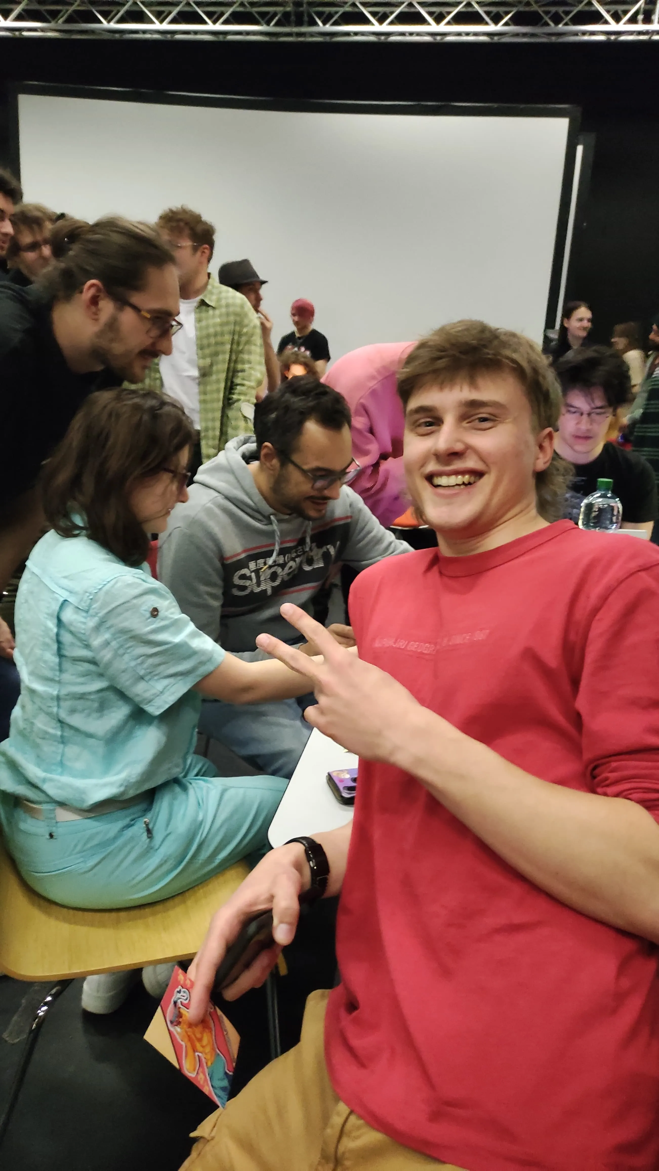Smiling team member flashing a peace sign in the crowded jam hall
